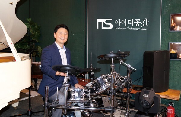 아이티공간은 지난 2020년 연구소 건물로 사용하던 1층 직원휴게실을 산업문화공간 ‘잇츠룸(It’s room)’을 조성했다. 현재 잇츠룸에서는 아이 티공간 후원으로 산업 전시뿐 아니라, 지역 내 다문화 가정 후원 등 다양한 행사가 진행되고 있다. 아이티공간 이영규 대표가 잇츠룸 내 드 럼 앞에 앉아 포즈를 취했다. [사진=아이티공간]<br>